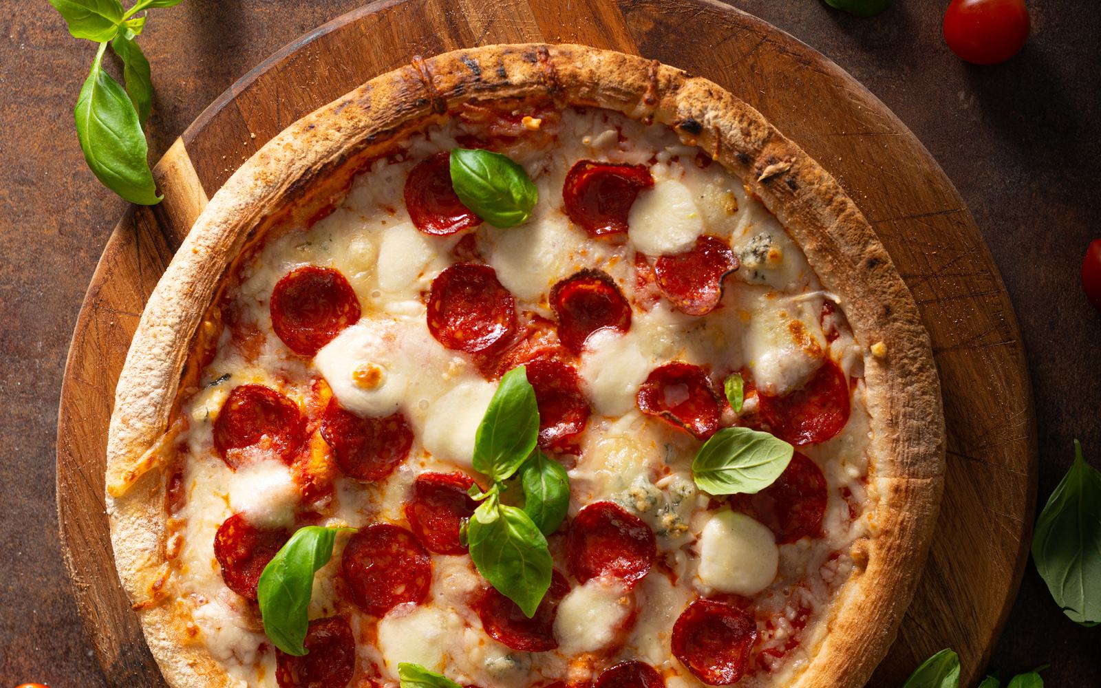 A stone-baked pepperoni pizza with mozzarella and basil